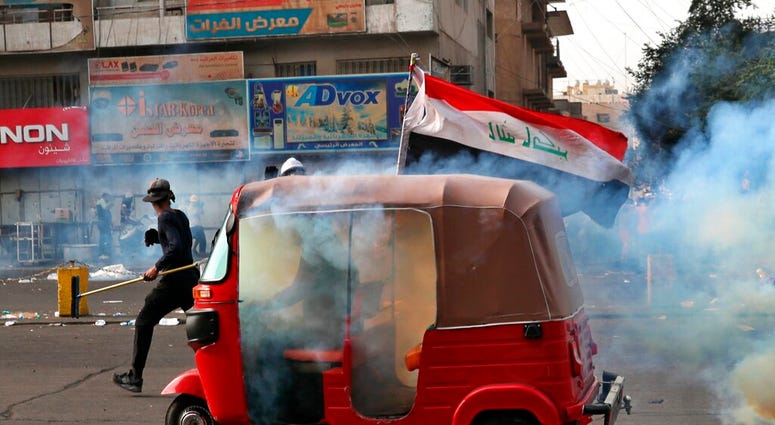 Riot police fire tear gas during clashes between Iraqi security forces and anti-Government protesters in Baghdad, Iraq, Thursday, Nov. 14, 2019. (AP Photo/Khalid Mohammed)