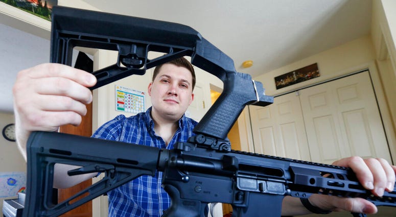 In this March 15, 2019 photo, Ryan Liskey displays a bump stock on top of his AR-15 at his home in Harrisonburg, Va. The ban on bump stocks is just a few days away and owners of the devices like Liskey are wondering what to do. (AP Photo/Steve Helber)