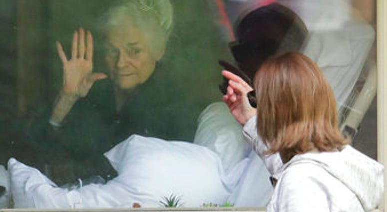 Judie Shape, left, who has tested positive for the coronavirus, waves to her daughter, Lori Spencer, right, Wednesday, March 11, 2020, at the Life Care Center in Kirkland, Wash. (AP Photo/Ted S. Warren) Judie Shape, left, who has tested positive for the coronavirus, waves to her daughter, Lori Spencer, right, Wednesday, March 11, 2020, at the Life Care Center in Kirkland, Wash. (AP Photo/Ted S. Warren)