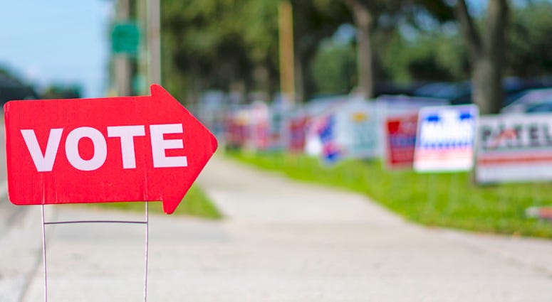 Sign directing voters to polling place with political signs in the background. Stock photo. (iStock / Getty Images Plus)