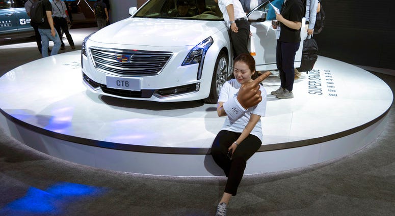 A woman poses for a photo in front of a CT6 Cadillac during the Consumer Electronics Show Asia 2018 in Shanghai, China on Friday, June 15, 2018. (AP Photo/Sam McNeil)