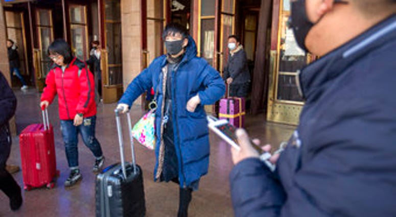 Travelers wear face masks as they walk outside of the Beijing Railway Station in Beijing, Monday, Jan. 20, 2020. China reported Monday a sharp rise in the number of people infected with a new coronavirus. (AP Photo/Mark Schiefelbein) Travelers wear face masks as they walk outside of the Beijing Railway Station in Beijing, Monday, Jan. 20, 2020. China reported Monday a sharp rise in the number of people infected with a new coronavirus. (AP Photo/Mark Schiefelbein)