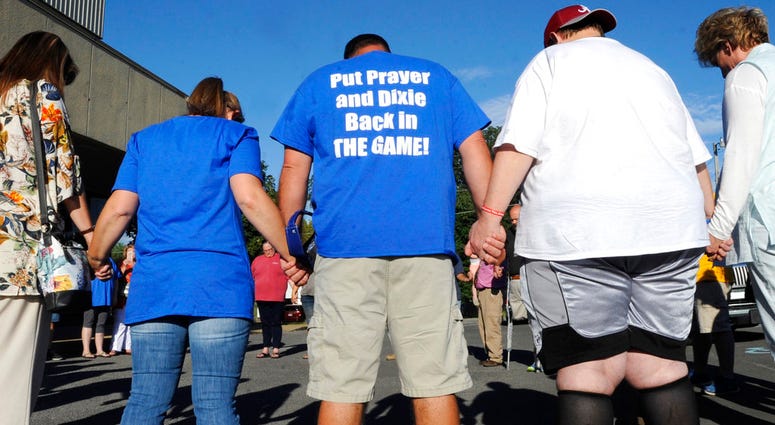 Opponents of a decision to quit playing "Dixie" as the high school fight song pray before a city school board meeting in Arab, Ala., on Thursday, Aug. 30, 2018. Critics of the decision, who also want to resume public prayers before high school football ga