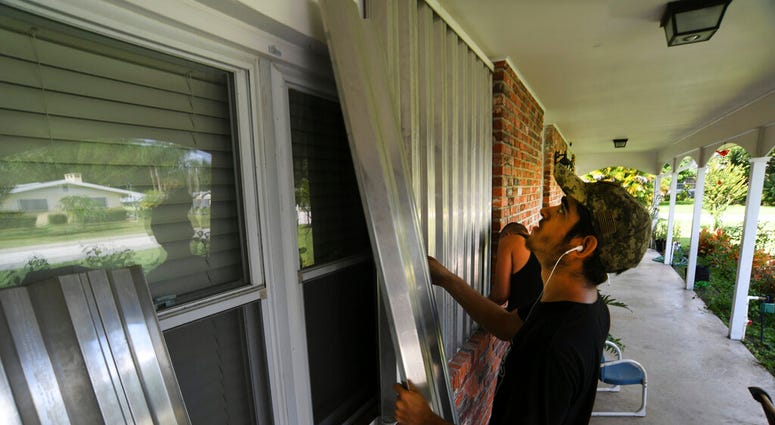 Richard Henson (foreground) and his uncle, Peter Henson, prepare their grandmother's house Thursday, Aug. 29, 2019, where she lives on Greenwood Drive in Fort Pierce, Fla., for the arrival of Hurricane Dorian. (Eric Hasert/TCPalm.com via AP)