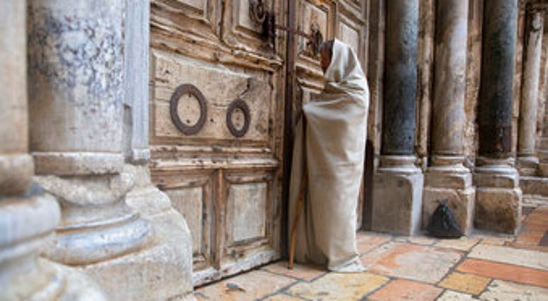 A Christian worshiper stands at the closed door of the Church of the Holy Sepulchre, believed by many Christians to be the site of the crucifixion and burial of Jesus Christ, in Jerusalem, Friday, April 10, 2020. (AP Photo/Sebastian Scheiner) A Christian worshiper stands at the closed door of the Church of the Holy Sepulchre, believed by many Christians to be the site of the crucifixion and burial of Jesus Christ, in Jerusalem, Friday, April 10, 2020. (AP Photo/Sebastian Scheiner)