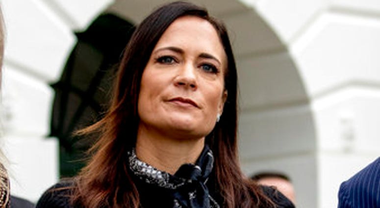 FILE- In this Oct. 3, 2019 file photo, White House press secretary Stephanie Grisham listens as President Donald Trump speaks to the media on the South Lawn of the White House in Washington. (AP Photo/Andrew Harnik) FILE- In this Oct. 3, 2019 file photo, White House press secretary Stephanie Grisham listens as President Donald Trump speaks to the media on the South Lawn of the White House in Washington. (AP Photo/Andrew Harnik)