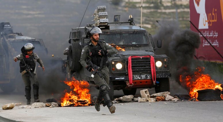Israeli border policemen move away from a burning vehicle during clashes with Palestinians at checkpoint Bet El near the West Bank city of Ramallah , Wednesday, March 27, 2019. (AP Photo/Majdi Mohammed)