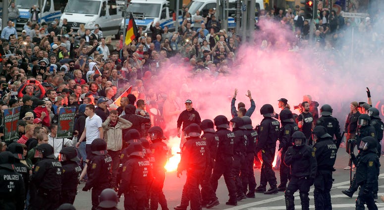 Protesters light fireworks during a far-right demonstration in Chemnitz, Germany, Monday, Aug. 27, 2018 after a man has died and two others were injured in an altercation between several people of "various nationalities." (AP Photo/Jens Meyer)