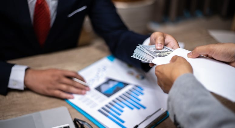 usinessman giving bribe money to partner in a corruption scam