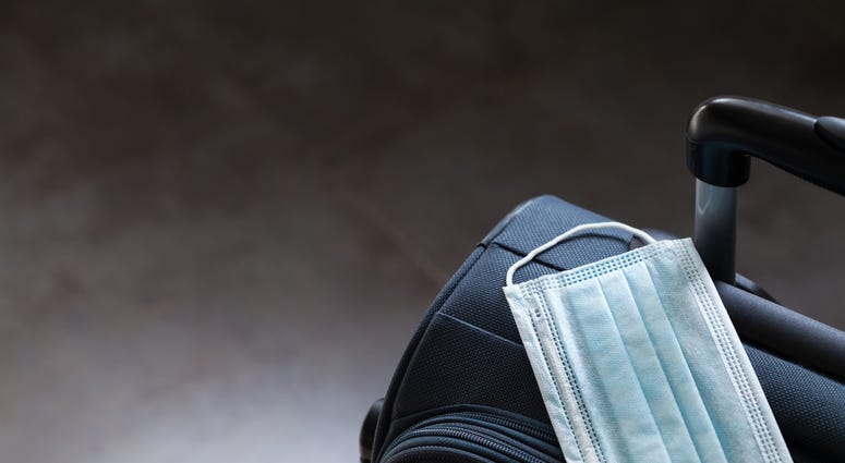 Travel suitcase and medical mask. The ban on travel during the epidemic of coronavirus and quarantine against corona virus or covid-19 concept.