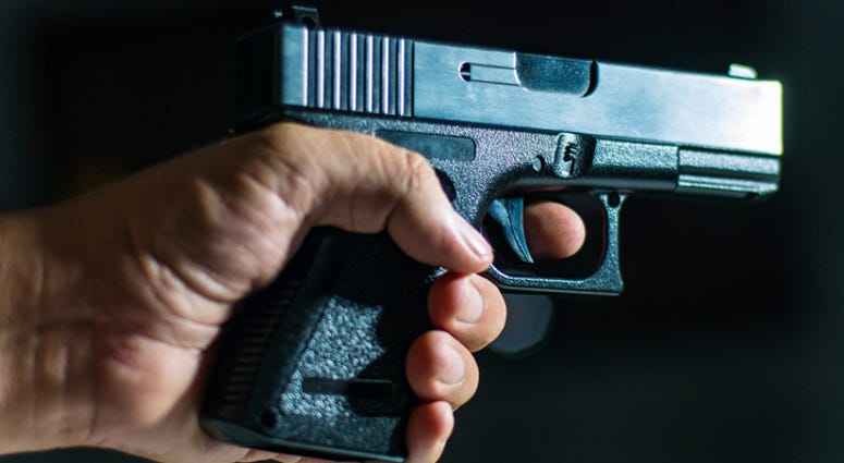 Man's hand holding a handgun on black