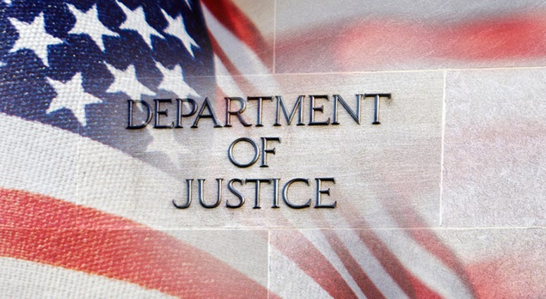 Department of Justice building sign with an American flag behind it