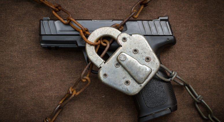 Pistol behind lock and chains symbolic of gun control.