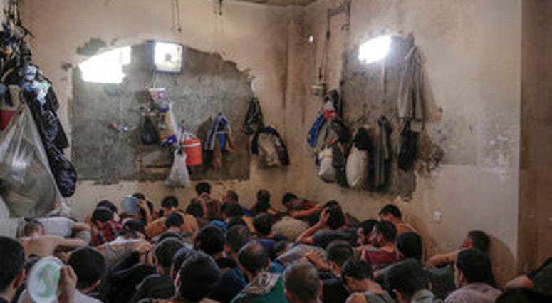 FILE - In this July 18, 2017 file photo, suspected Islamic State members sit inside a small room in a prison south of Mosul. (AP Photo/Bram Janssen, File)