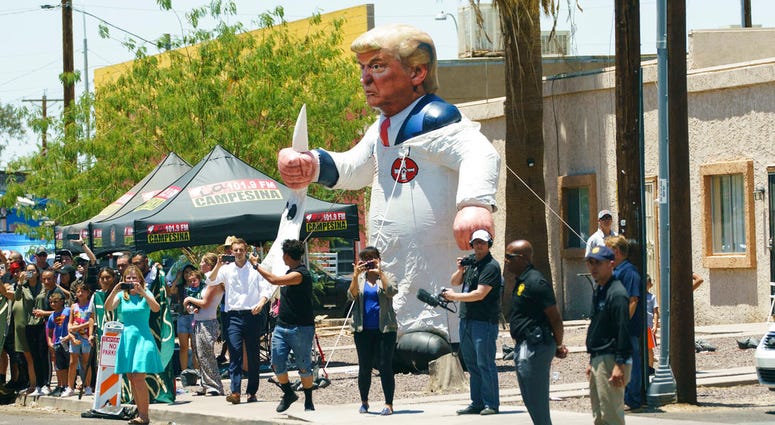 Protesters place a large inflatable balloon in the likeness of President Donald Trump dressed in a Ku Klux Klan sheet across the street from Southwest Key Campbell, a shelter for children that have been separated from their parents, in Phoenix, Ariz., Thu