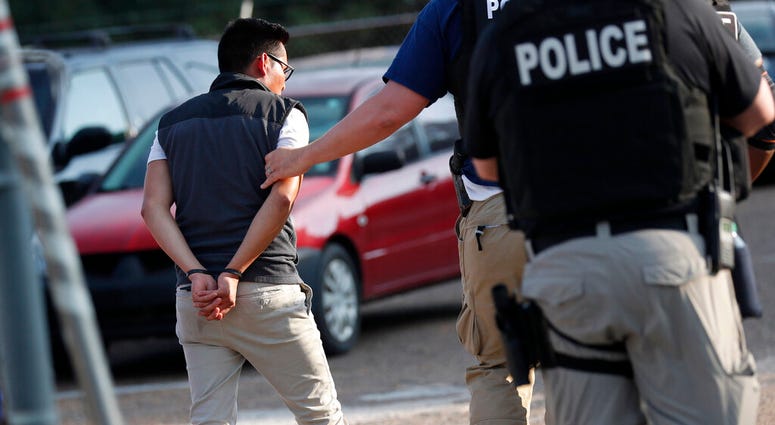 A man is taken into custody at a Koch Foods Inc. plant in Morton, Miss., on Wednesday, Aug. 7, 2019. U.S. immigration officials raided several Mississippi food processing plants on Wednesday. (AP Photo/Rogelio V. Solis)