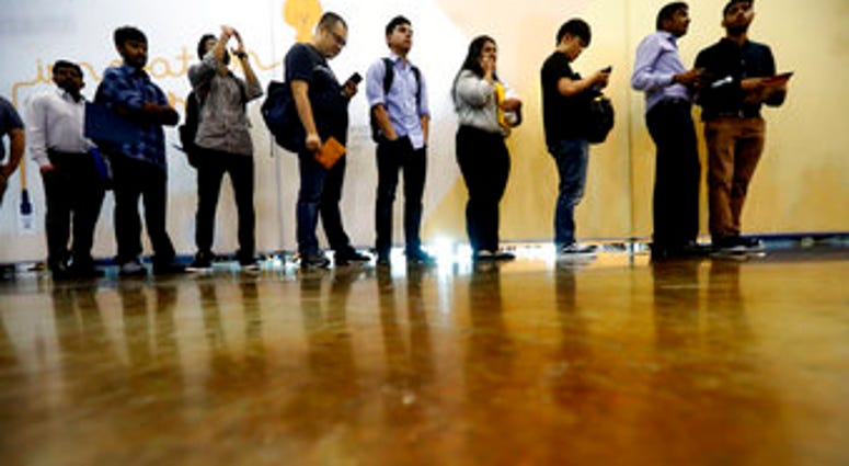 In this Sept. 17, 2019, photo job seekers line up to speak to recruiters during an Amazon job fair in Dallas. On Friday, Oct. 4, the U.S. government issues the September jobs report. (AP Photo/LM Otero)