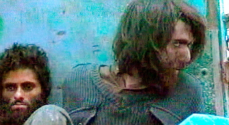 FILE - This file image taken Dec. 1, 2001, from television footage in Mazar-i-Sharif, Afghanistan, shows John Walker Lindh, right, claiming to be an American Taliban volunteer. (AP Video, File)
