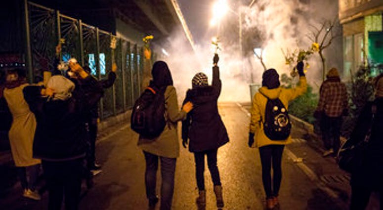 In this photograph taken Saturday, Jan. 11, protesters hold flowers as tear gas fired by police rises at a demonstration in front of Amir Kabir University in Tehran, to remember victims of a Ukrainian airplane shot down by an Iranian missile. (AP Photo) In this photograph taken Saturday, Jan. 11, protesters hold flowers as tear gas fired by police rises at a demonstration in front of Amir Kabir University in Tehran, to remember victims of a Ukrainian airplane shot down by an Iranian missile. (AP Photo)