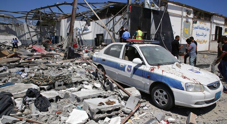 Debris covers the ground and an emergency vehicle after an airstrike at a detention center in Tajoura, east of Tripoli in Libya, Wednesday, July 3, 2019. An airstrike hit the detention center for migrants Wednesday, killing several. (AP Photo/Hazem Ahmed)