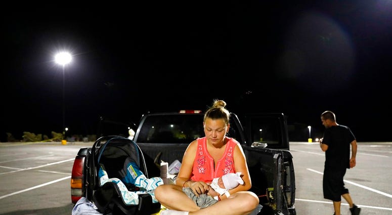 In this Monday, Oct. 15, 2018 file photo, Lorrainda Smith sits with her 2-day-old son, Luke, as she and her husband contemplate sleeping in their truck in a parking lot after their home was damaged from Hurricane Michael. (AP Photo/David Goldman, File)