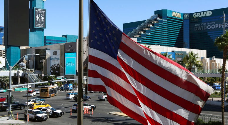 FILE - In this Oct. 2, 2017 file photo, an American flag waves near a police barricade on the Las Vegas Strip with the MGM Grand hotel and casino in the background after a mass shooting in Las Vegas. The unprecedented move from MGM Resorts International t