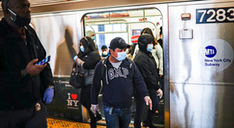 Subway riders, wearing personal protective equipment due to COVID-19 concerns, step off a train, Tuesday, April 7, 2020, in New York. (AP Photo/John Minchillo) Subway riders, wearing personal protective equipment due to COVID-19 concerns, step off a train, Tuesday, April 7, 2020, in New York. (AP Photo/John Minchillo)