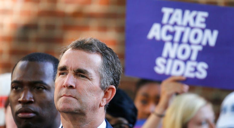 Virginia Gov. Ralph Northam, right, listens to speakers along with Richmond Mayor Levar Stoney, left, during a rally at the State Capitol in Richmond, Va., Tuesday, July 9, 2019. (AP Photo/Steve Helber)