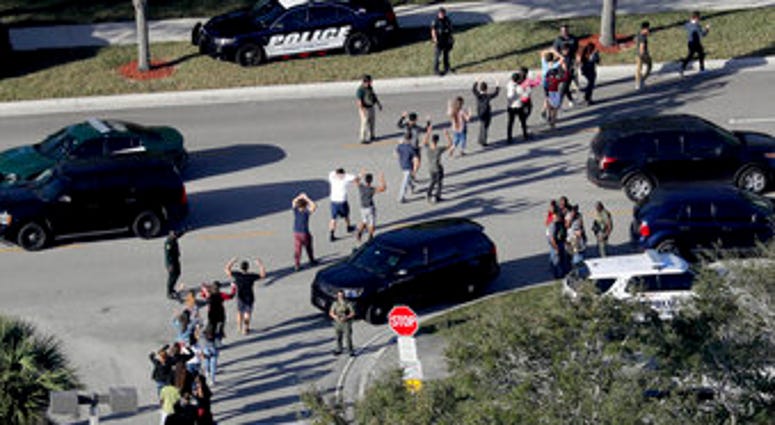 FILE - In this Wednesday, Feb. 14, 2018, file photo, students hold their hands in the air as they are evacuated by police from Marjory Stoneman Douglas High School in Parkland, Fla. (Mike Stocker/South Florida Sun-Sentinel via AP, File) FILE - In this Wednesday, Feb. 14, 2018, file photo, students hold their hands in the air as they are evacuated by police from Marjory Stoneman Douglas High School in Parkland, Fla. (Mike Stocker/South Florida Sun-Sentinel via AP, File)