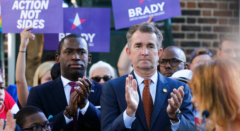 Virginia Gov. Ralph Northam, right, applauds speakers along with Richmond Mayor Levar Stoney, left, during a rally at the State Capitol in Richmond, Va., Tuesday, July 9, 2019. (AP Photo/Steve Helber)