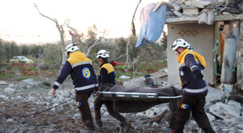 In this photo provided by the Syrian Civil Defense White Helmets, Syrian White Helmet civil defense workers carry a victim next to a destroyed house that was hit by Russian airstrike. (Syrian Civil Defense White Helmets via AP) In this photo provided by the Syrian Civil Defense White Helmets, Syrian White Helmet civil defense workers carry a victim next to a destroyed house that was hit by Russian airstrike. (Syrian Civil Defense White Helmets via AP)