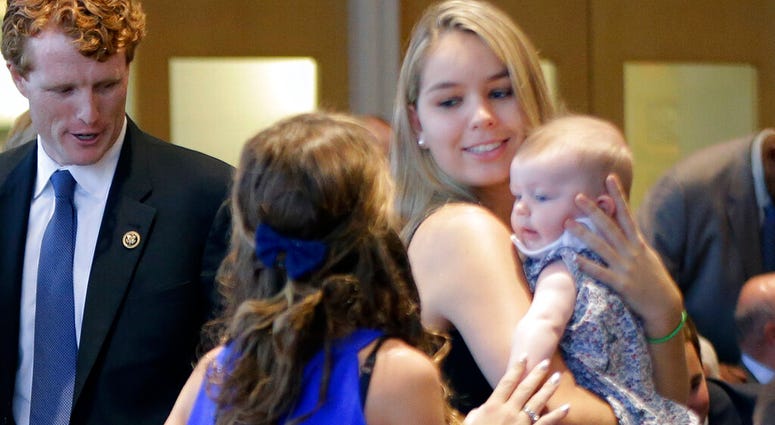In this Sept. 20, 2016, photo, Saoirse Kennedy Hill, right, granddaughter of Ethel Kennedy and her late husband Robert F. Kennedy, holds a relative's baby before a ceremony for naming the Robert Kennedy Navy Ship. (AP Photo/Elise Amendola)