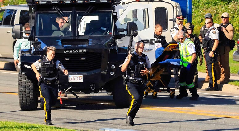 Police and RCMP officers survey the area of a shooting in Fredericton, New Brunswick, Canada on Friday, Aug. 10, 2018. Fredericton police say two officers were among four people who died. (Keith Minchin/The Canadian Press via AP)
