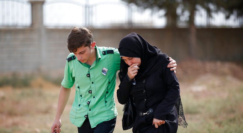 A member of the family of ten-month-old Mohammed Omar Saar, killed during incoming shelling from Syria Thursday, is helped following the funeral in Akcakale, Sanliurfa province, Turkey, at the border with Syria. (AP Photo/Lefteris Pitarakis)