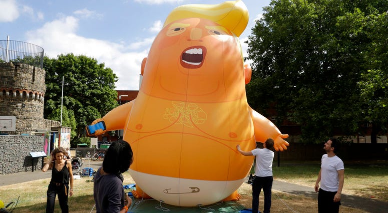 In this photo taken on Tuesday, July 10, 2018, a six-meter high cartoon baby blimp of U.S. President Donald Trump stands inflated during a practice session in Bingfield Park, north London. (AP Photo/Matt Dunham)