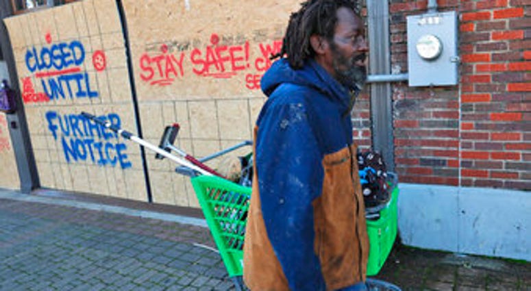 FILE - In this Tuesday, March 31, 2020 file photo, Vincent Amos, who identified himself as homeless, pulls a shopping cart with his belongings amid businesses closed by concerns of the COVID-19 coronavirus in Dallas. (AP Photo/LM Otero) FILE - In this Tuesday, March 31, 2020 file photo, Vincent Amos, who identified himself as homeless, pulls a shopping cart with his belongings amid businesses closed by concerns of the COVID-19 coronavirus in Dallas. (AP Photo/LM Otero)