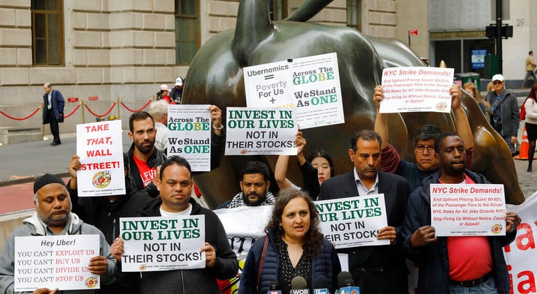 Uber drivers protest next to the Charging Bull statue in New York's financial district, Wednesday, May 8, 2019. The protests arrive just ahead of Uber's initial public stock offering, which is planned for Friday. (AP Photo/Mark Lennihan)