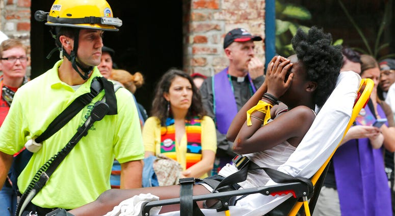 FILE - In this Aug. 12, 2017, file photo, an emergency employee helps an injured person after a neo-Nazi drove his car into a group of counter-protesters at a white nationalist rally in Charlottesville, Va. (AP Photo/Steve Helber, File)
