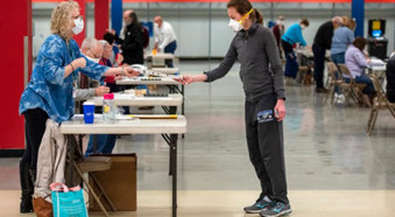 Bridget McDonald, right, receives a ballot from poll worker Patty Piek-Groth on Tuesday, April 7, 2020, at the Janesville Mall in Janesville, Wis. (Angela Major/The Janesville Gazette via AP) Bridget McDonald, right, receives a ballot from poll worker Patty Piek-Groth on Tuesday, April 7, 2020, at the Janesville Mall in Janesville, Wis. (Angela Major/The Janesville Gazette via AP)
