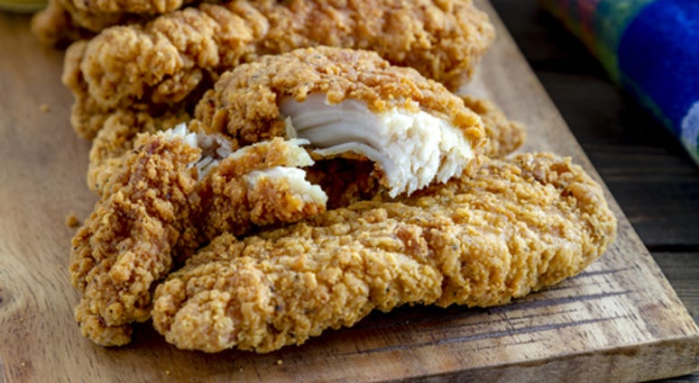 Close up of chicken strips on wooden cutting board
