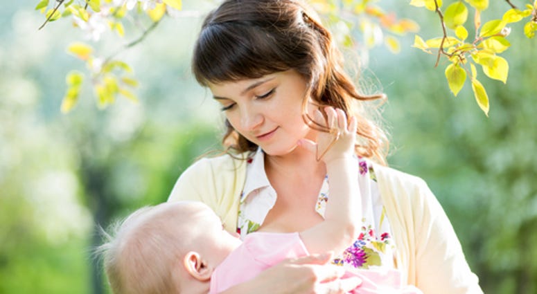 Young mother breast feeding her baby girl outdoors