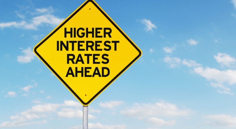 Roadsign of higher interest rates ahead against blue sky