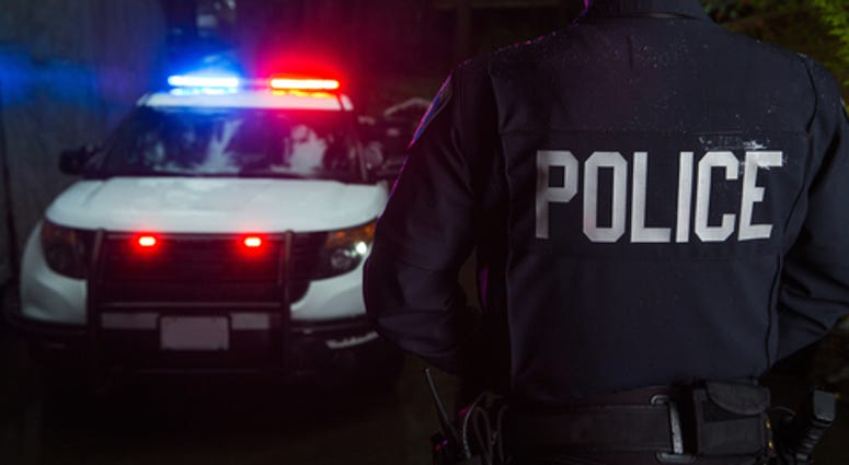 A police officer standing near his car with the light on