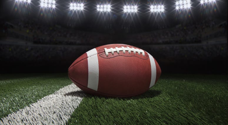 Low angle view of college style football on a yard line of a football field under stadium lights