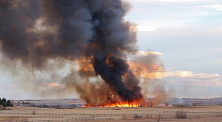 A wildfire in Colorado produces a plume of dark smoke rising into the sky.