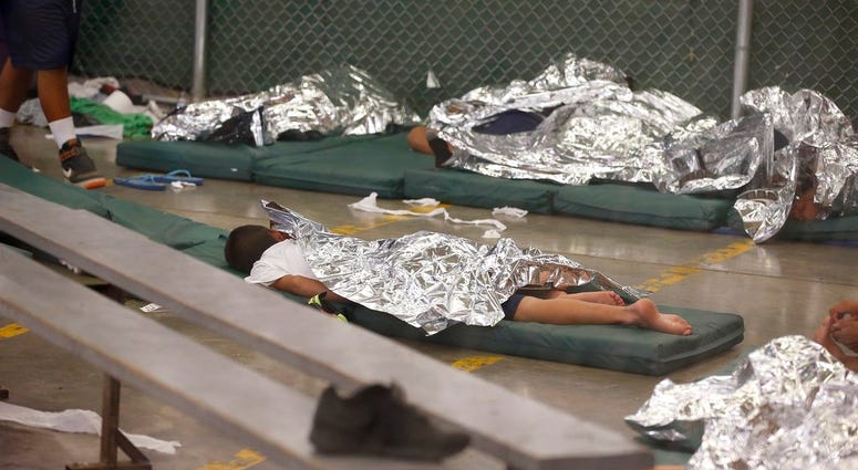 FILE - In this June 18, 2014, file photo, young boys sleep in a holding cell where hundreds of mostly Central American immigrant children are being processed and held at the U.S. Customs and Border Protection Nogales Placement Center in Nogales, Ariz. CPB
