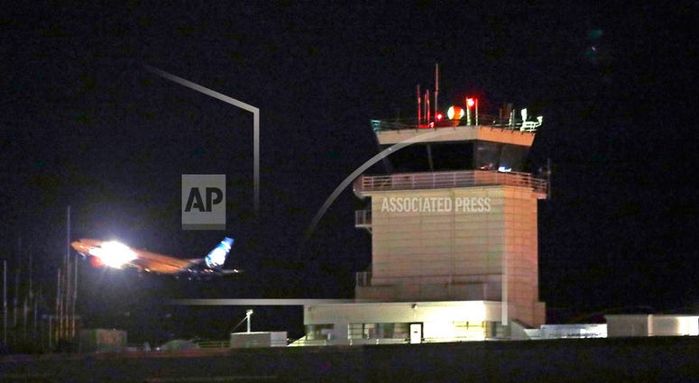 A plane flies past a control tower at Sea-Tac International Airport Friday evening, Aug. 10, 2018, in SeaTac, Wash. An airline mechanic stole an Alaska Airlines plane without any passengers and took off from Sea-Tac International Airport in Washington sta