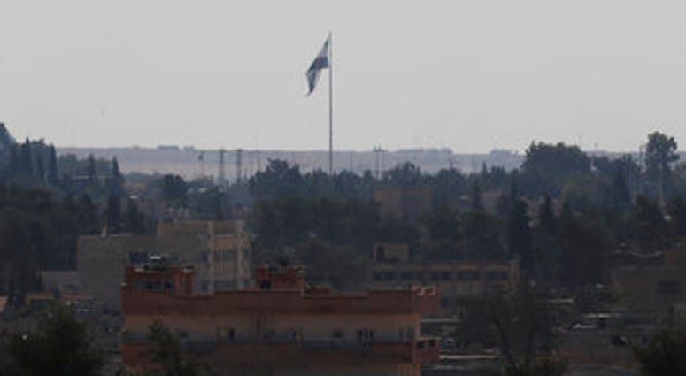 In this photo taken from the Turkish side of the border between Turkey and Syria, in Akcakale, Sanliurfa province, southeastern Turkey, Syria's opposition flag flies on a pole in Tal Abyad, Syria, Wednesday, Oct. 23, 2019. (AP Photo/Lefteris Pitarakis)