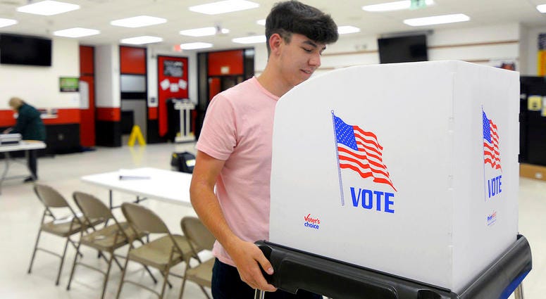 James Fitzgerald, of Boonsboro, Md., a poll worker for the last four months, sets up a voting booth at Northern Middle School in Hagerstown, Md.,