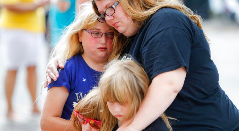 Mourners embrace after bringing flowers to a makeshift memorial Tuesday, Aug. 6, 2019, for the slain and injured in the Oregon District after a mass shooting that occurred early Sunday morning, in Dayton, Ohio. (AP Photo/John Minchillo)